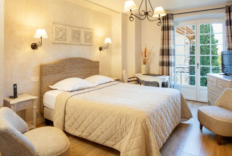 Room with double bed decorated in light tones at La Bastide de Tourtour