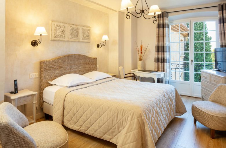Room with double bed decorated in light tones at La Bastide de Tourtour