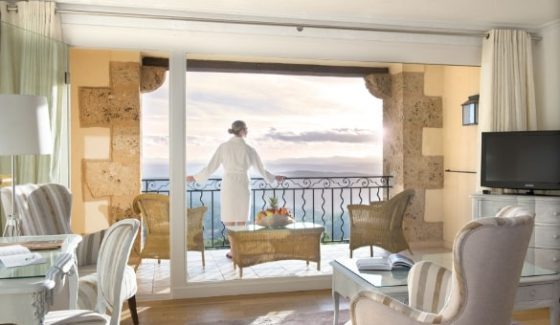 Woman in bathrobe gazing at the horizon from the balcony of her room at the Bastide de Tourtour - hotel spa var