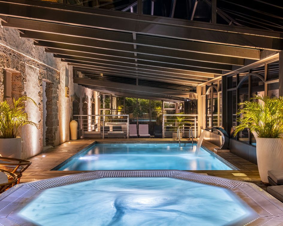 Swimming pool and jacuzzi in the glass roof of the Bastide de Tourtour by night with light - hotel spa var