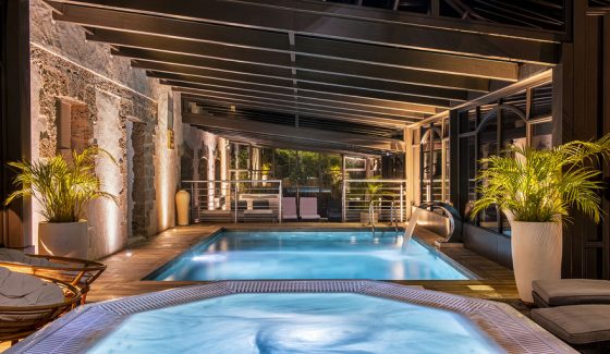 Swimming pool and jacuzzi in the glass roof of the Bastide de Tourtour by night with light - hotel spa var