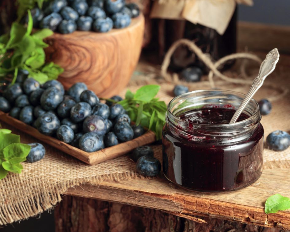 Blueberry jam with fresh berries on an old wooden table.