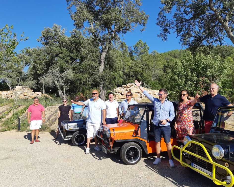 Happy people posing in front of moke cars